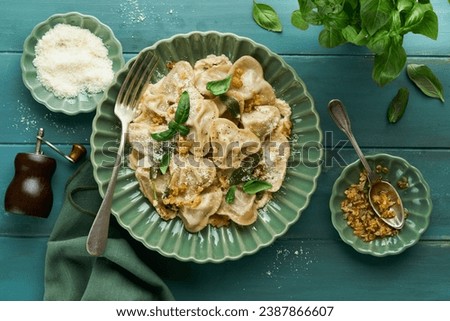 Homemade italian ravioli pasta in heart shape with beef meat, cheese sauce, caramelized onions, basil and saffron on old wooden blue background. Food cooking menu ingredients background. Top view.