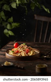 Homemade Italian spaghetti pasta with sauce, tomatoes, basil and parmesan. Traditional Italian cuisine. Served on a dark table with a rustic wooden background. Vertical - Shutterstock ID 2065893965