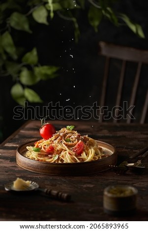 Homemade Italian spaghetti pasta with sauce, tomatoes, basil and parmesan. Traditional Italian cuisine. Served on a dark table with a rustic wooden background. Vertical