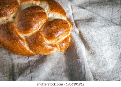 Homemade Jewish traditional challah bread on linen tablecloth. Top view of fresh baked challah