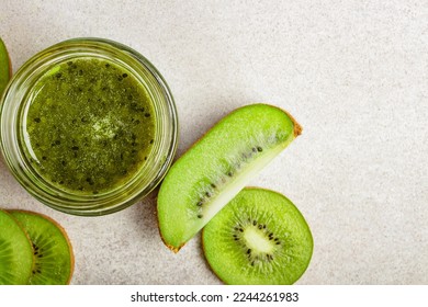 Homemade kiwi jam in a jar and kiwi slyces on concrete background with copy space. - Shutterstock ID 2244261983
