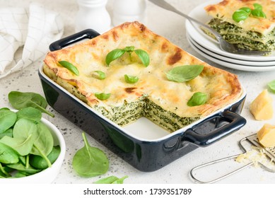 Homemade lasagna with spinach and ricotta in a blue ceramic mold. Traditional italian dish. A piece of lasagna on a white plate. Selective focus - Shutterstock ID 1739351789