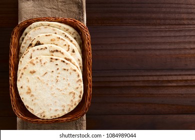 Homemade Leavened Indian Naan Flatbread In Basket, Photographed Overhead On Dark Wood