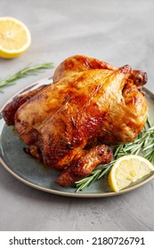 Homemade Lemon And Herb Rotisserie Chicken On A Plate On A Gray Surface, Side View. 