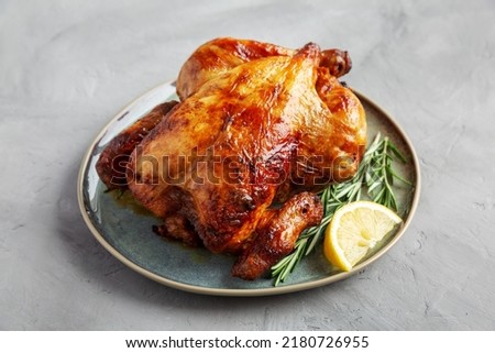 Homemade Lemon and Herb Rotisserie Chicken on a Plate on a gray background, side view. 