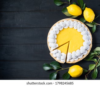 Homemade Lemon Pie With Meringue, Cutted Piece, With Fresh Lemons On Black Wooden Background, Top View, Copyspace.