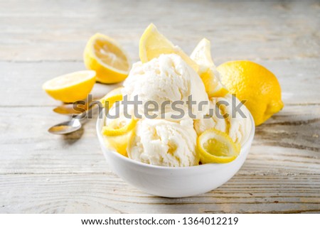 Homemade lemon vanilla ice cream with fresh lemon slices. Sweet and sour summer dessert. Wooden background copy space