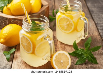 Homemade lemonade with lemon and mint in mason jar on wooden table. Refreshing summer drink. Drink making ingredients for lemonade.