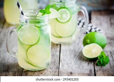 homemade lemonade with lime, mint in a mason jar on a wooden rustic table