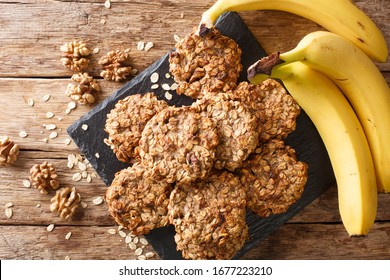 Homemade low-calorie banana cookies with oatmeal and walnuts close-up on a slate board on the table. Horizontal top view from above