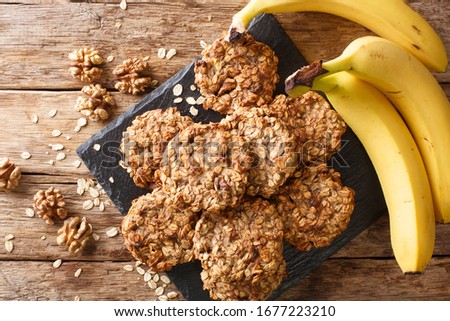 Homemade low-calorie banana cookies with oatmeal and walnuts close-up on a slate board on the table. Horizontal top view from above
