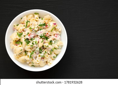 Homemade Macaroni Salad In A White Bowl On A Black Surface, Top View. Flat Lay, Overhead, From Above. Copy Space.