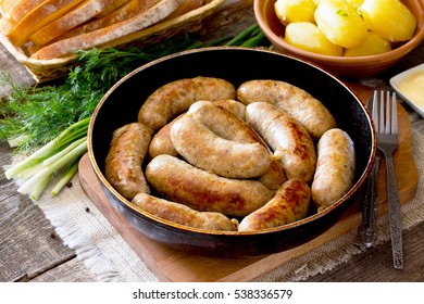 Homemade meat raw sausage on a cast iron frying pan, vegetables, herbs and boiled potatoes on a rustic background. - Powered by Shutterstock