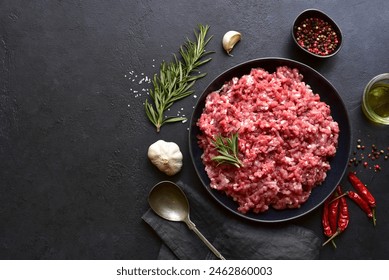 Homemade minced meat with ingredients for making in a bowl over dark slate, stone or concrete background. Top view. - Powered by Shutterstock