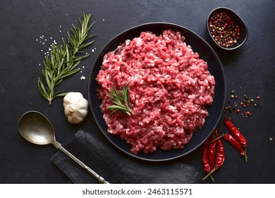 Homemade minced meat with ingredients for making in a bowl over dark slate, stone or concrete background. Top view. - Powered by Shutterstock