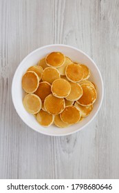 Homemade Mini Pancakes Cereal In A White Bowl On A White Wooden Background, Top View. Flat Lay, Overhead, From Above.