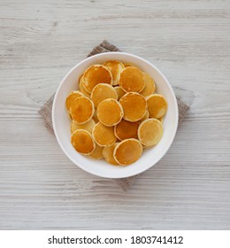 Homemade Mini Pancakes Cereal In A White Bowl On A White Wooden Background, Top View. Flat Lay, Overhead, From Above.