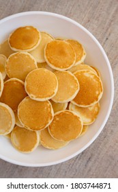 Homemade Mini Pancakes Cereal In A White Bowl, Top View. Flat Lay, Overhead, From Above. 