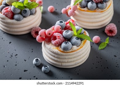 Homemade mini Pavlova dessert with whipped cream and frozen fruit. Dessert made of meringue with frozen berries and cream.