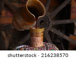 Homemade Moldovan wine pouring from a traditional homemade clay jug into a clay cup standing on a traditional patterned towel