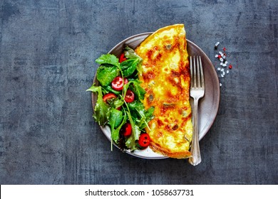 Homemade mushroom omelette with salad on plate over dark concrete copy space background. Healthy food concept. Flat lay, top view