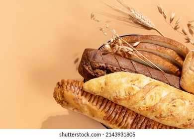 Homemade natural breads. Fresh loafs of bread in the blue basket with ears of rye and wheat on a beige background with copy space. Crunchy french baguettes, slices of bread and a bun. Soft focus  - Shutterstock ID 2143931805