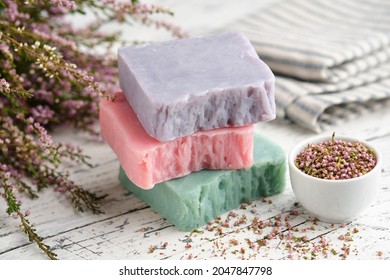 Homemade natural soap bars and heather flowers on white table. Bars of organic soap.