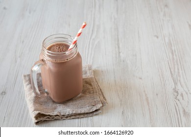 Homemade New England Chocolate Milkshake in a Glass Jar Mug on a white wooden background, low angle view. Copy space.