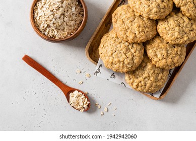 Homemade oatmeal cookies with banana, oats and nuts on a wooden tray and oats flakes on white background, top view, close up. Healthy food. Oatmeat biscuits recipe. Horizontal
