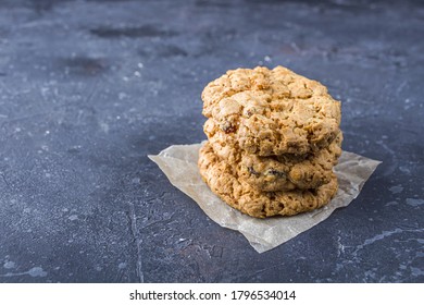 Homemade Oatmeal Cookies With Raisins And Chocolate On Dark Background. Healthy Snack Before Bedtime Or Nutritious Breakfast. Fresh Baked Wholegrain Cookies