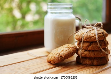 homemade oatmeal cookies tied with a thread, next to a jar of milk. It lies on a light wooden background. rustic style