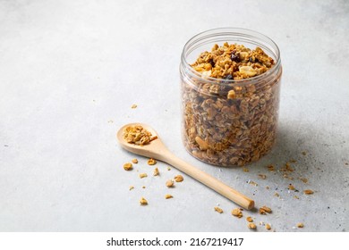Homemade oatmeal granola in open glass jar with spoon on ligth grey background. Healthy breakfast concept. Organic oat, hazelnut, peanut, raisin and sunflower seeds. Copy space. Selective focus. - Powered by Shutterstock