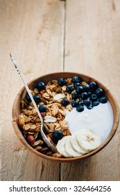 Homemade oatmeal granola with peanuts, blueberry and banana in wooden bowl, sunny morning - Shutterstock ID 326464256