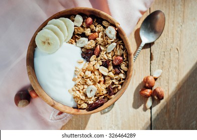 Homemade oatmeal granola with peanuts, blueberry and banana in wooden bowl, sunny morning - Shutterstock ID 326464289