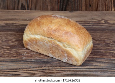 Homemade, Oblong, Golden, Crunchy Bread. A Natural, Fresh, Delicious Loaf. Tasty, Freshly Baked Batch On A Brown, Wooden, Rustic Table. Close-up View.