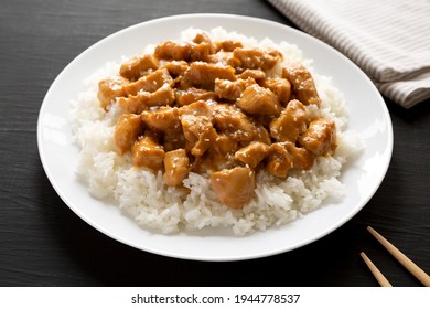 Homemade Orange Chicken With White Rice On A White Plate On A Black Background, Side View. Close-up.