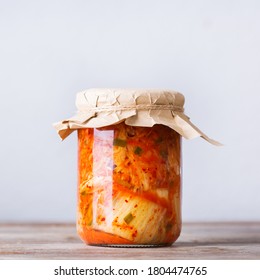Homemade organic traditional korean kimchi cabbage salad in a glass jar on a wooden table. Fermented vegetarian, vegan preserved gut health food concept