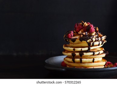 Homemade Pancake with raspberries, almonds and chocolate on a black background