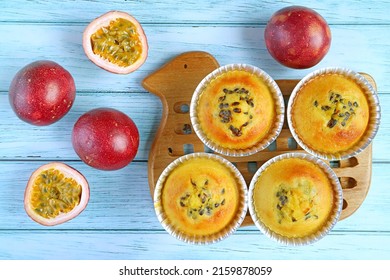 Homemade Passion Fruit Muffins in Molds on Breadboard with Fresh Fruits Scattered on Pale Blue Table