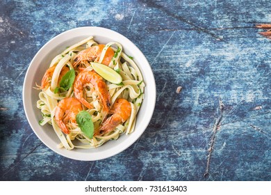 Homemade Pasta With Fried Shrimps And Basil On Rustic Wooden Blue Background. Space For Text. Pasta With Seafood In Plate. Top View. Closeup. Mediterranean Cuisine. Pasta For Dinner Or Lunch. Overhead