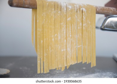 Homemade pasta linguine hanging on wooden stick to dry. Homemade Italian tagliatelle hanging on a pasta drying stick. - Powered by Shutterstock