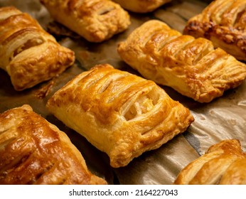 Homemade pastries freshly baked puff pastry puffs with apples on baking paper close-up. Bakery products