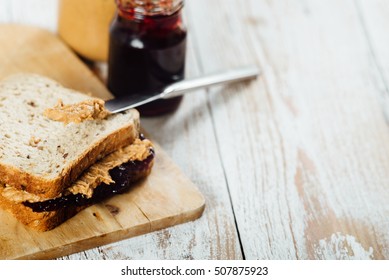 Homemade peanut butter and cherry jelly sandwich on wooden background