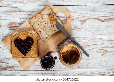 Homemade peanut butter and heart shaped jelly sandwich on wooden background - Shutterstock ID 504726622