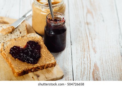 Homemade peanut butter and heart shaped jelly sandwich on wooden background