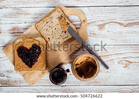 Homemade peanut butter and heart shaped jelly sandwich on wooden background
