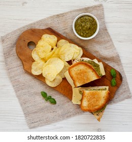 Homemade Pesto Chicken Sandwich With Potato Chips On A Rustic Wooden Board, Overhead View. Flat Lay, From Above, Top View.