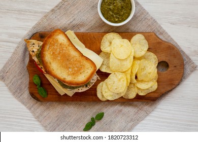 Homemade Pesto Chicken Sandwich With Potato Chips On A Rustic Wooden Board, Top View. Flat Lay, From Above, Overhead.