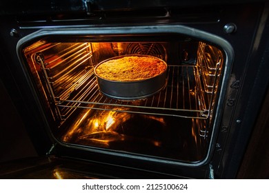 A homemade pie is prepared and baked in a special baking dish in an electric oven in the kitchen. View of the finished hot cake with the oven door open. Delicious apple dessert. - Shutterstock ID 2125100624