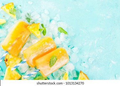 Homemade Pineapple Popsicles on Ice with fresh Pineapple slices and mint, on light blue background copy space top view - Powered by Shutterstock